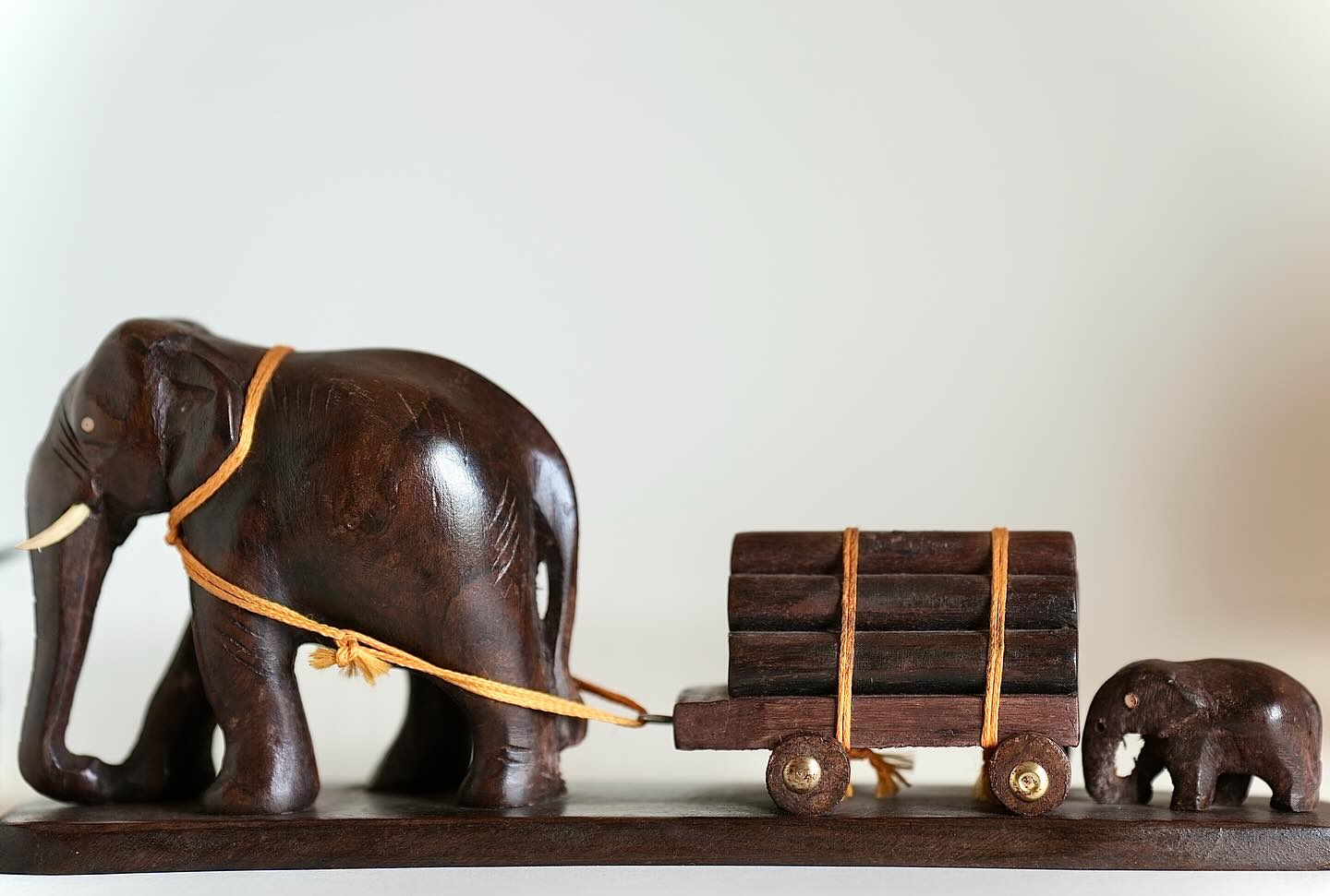 Elephant pulling a loaded wooden cart with a calf assisting from behind. Size: 12 inches.